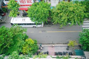 un autobús está estacionado en una calle con árboles en Dai A Hotel, en Da Nang