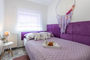 a purple bed with a tray with a teddy bear on it at Lu Apartments in Oświęcim