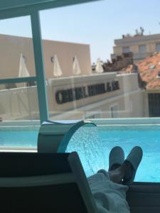 a person laying on a chair next to a swimming pool at Cristal Hôtel & Spa in Cannes