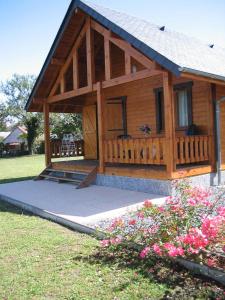 Cabaña de madera grande con porche y flores en Chalets du Lac en Arcizans-Avant