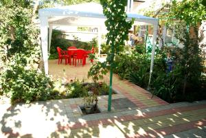 a patio with a red table and chairs in a greenhouse at Guest Нouse in Odesa