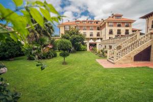 un grande edificio con un cortile verde con scala di Hotel Spa Villa Pasiega a Hoznayo