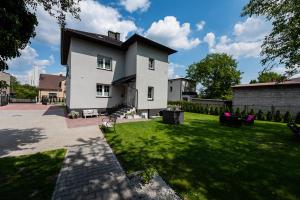 a white house with a yard with green grass at Lu Apartments in Oświęcim