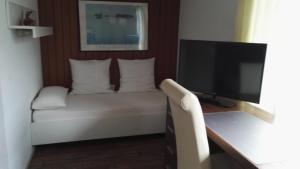 - un salon avec un canapé et une télévision dans l'établissement Hotel Römerhof, à Sarrebruck