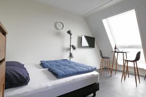 a bedroom with a bed with a blue blanket on it at Ut Endt Vlieland in Oost-Vlieland