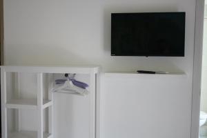 einen Flachbild-TV an einer weißen Wand mit einem Regal in der Unterkunft Belice rooms in Salemi