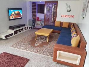 ein Wohnzimmer mit einem blauen Sofa und einem Tisch in der Unterkunft APPARTEMENT "NESRINE" Kélibia in Kelibia