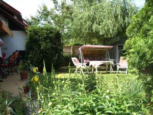 einen Garten mit zwei Stühlen und einem Tisch im Hof in der Unterkunft Apartmanház Gabriella in Harkány