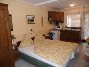 a bedroom with a bed and a kitchen at Apartmanház Gabriella in Harkány