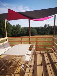 a picnic table on a deck with a red canopy at Roulotte de la basse biguerie proche zoo de la flèche in Saint-Jean-de-la-Motte