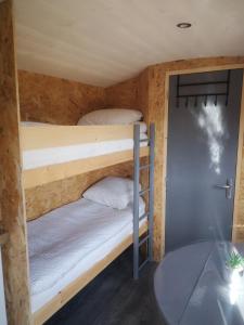 two bunk beds in a small room with a table at Roulotte de la basse biguerie proche zoo de la flèche in Saint-Jean-de-la-Motte