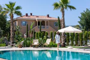 a woman walking by a swimming pool in front of a house at Zigo's Hotel in Muğla