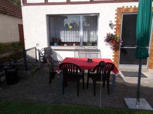 einen Tisch und Stühle mit einem roten Tisch und einem Fenster in der Unterkunft Ferienhaus Klinder in Bad Arolsen