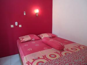 a red bedroom with a bed with pink sheets and pillows at Kancil homestay in Pangandaran