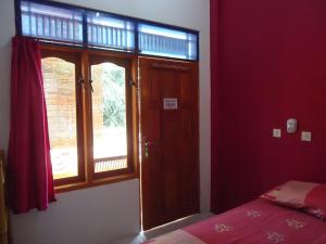 a bedroom with red walls and a bed and a window at Kancil homestay in Pangandaran +2 photos