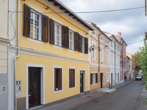 a yellow building with brown shuttered windows on a street at Apartmaji Diversorio in Izola