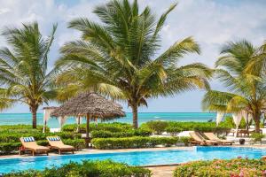 a resort pool with palm trees and chairs and the ocean at Next Paradise Boutique Resort in Pwani Mchangani