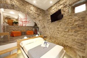 Habitación con pared de piedra, cama y TV. en Arpaiu, en Manarola