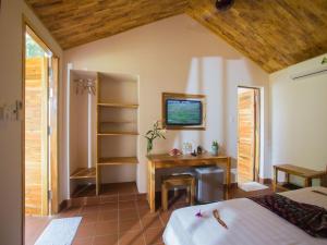 a bedroom with a bed and a desk in a room at La Mer Resort, Phú Quốc in Phú Quốc