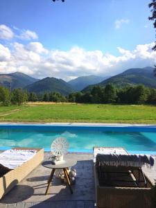 a pool with a table and chairs and a view of mountains at Marie Chalet in Breaza