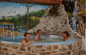 a man and two women in a jacuzzi in a stone tub at Hotel Ortles Dolomiti Walking & Spa in Cogolo