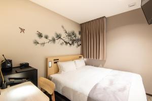 um quarto de hotel com uma cama, uma secretária e uma cadeira em La'gent Hotel Shinjuku Kabukicho em Tóquio