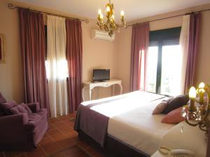 a bedroom with a bed and a chair and a window at Hotel Sindhura in Vejer de la Frontera