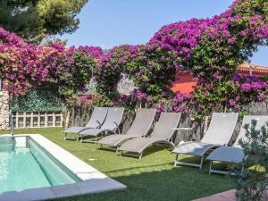 - un groupe de chaises longues à côté d'une piscine avec des fleurs violettes dans l'établissement Villa with private pool and sublime views, à Èze