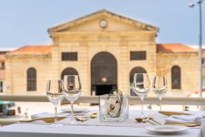 four wine glasses sitting on a table in front of a building at Kydon The Heart City Hotel in Chania