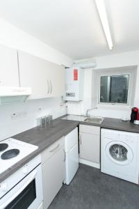 a white kitchen with a sink and a washing machine at Greyfriars Flat in Perth