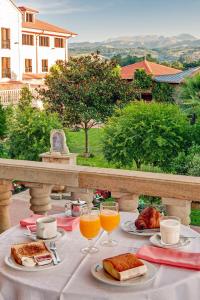 una mesa con platos de comida y vasos de zumo de naranja en Hotel Spa Villa Pasiega, en Hoznayo