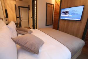 a bedroom with a white bed with a flat screen tv at Solun's Riverside Rooms in Skopje