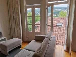 uma sala de estar com um sofá e uma grande janela em Mezzanine Apartment em Guimarães