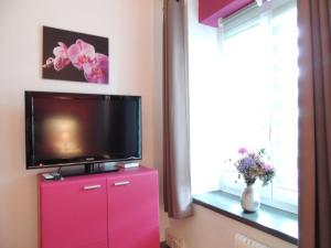 a tv on top of a red dresser in a room at Hotel de la Gare in Cousset 