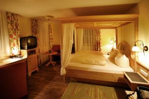 a bedroom with a canopy bed and a television at Landgasthof Hubertus - Braugasthof und Wellnesshotel im Allgäu in Apfeltrang