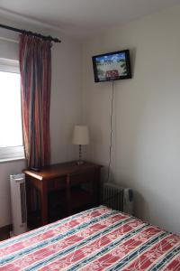 um quarto com uma cama e uma televisão na parede em Mafra Guest House em Mafra