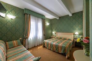 a hotel room with a bed and a couch at Hotel Villa Delle Palme in Venice-Lido