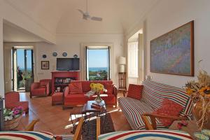 uma sala de estar com sofás vermelhos e uma televisão em Villa Praiola - Exclusive seafacing mansion with pool and Jacuzzi em San Leonardello