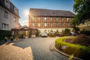 un grand bâtiment avec des voitures garées devant lui dans l'établissement Romantik Hotel am Brühl, à Quedlinbourg