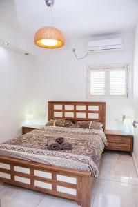 1 dormitorio con 1 cama grande con marco de madera en Apartments4you Dinara, en Bat Yam