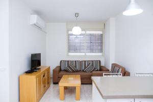 a living room with a couch and a tv at Apartments4you Dinara in Bat Yam