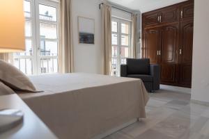 ein Schlafzimmer mit einem großen Bett und einem Stuhl in der Unterkunft Apartamento Centro La Paz by CasaTuristica in Ronda