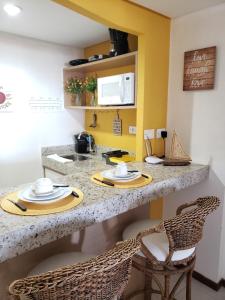 a kitchen with a counter with plates and chairs at Pipas Ocean Flat - Vista Mar in Pipa +5 photos