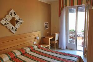 a bedroom with a bed and a desk and a window at Albergo Fiorita in Bardolino