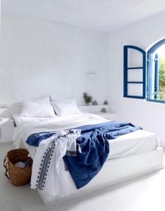 a white bedroom with a blue and white bed at Villa Ippocampi - Adults Only in Koutouloufari