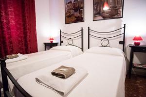 3 camas en una habitación con sábanas blancas y toallas en B&B Villa Adriana, en Tívoli