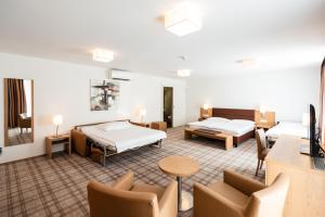 um quarto de hotel com duas camas e uma mesa e cadeiras em Central City Hotel Rochat em Basileia