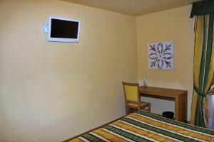 Albergo Fiorita في باردولينو: غرفة نوم مع سرير ومكتب وتلفزيون على الحائط
