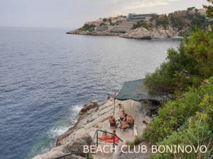 a group of people sitting on a cliff near the water at Rooms Villa Garden in Dubrovnik