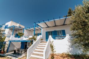 een wit huis met blauwe ramen en trappen bij Cyclades Luxury Studios in Nea Potidaea